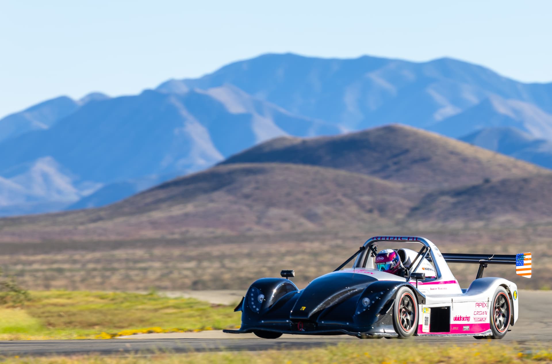 Radical race car cornering at INDE Motorsports Ranch with the Arizona mountains behind
